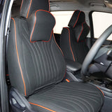 A set of black car seat covers with red detailing installed in a car interior, including headrest pillows.