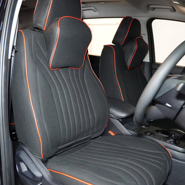 A set of black car seat covers with red detailing installed in a car interior, including headrest pillows.