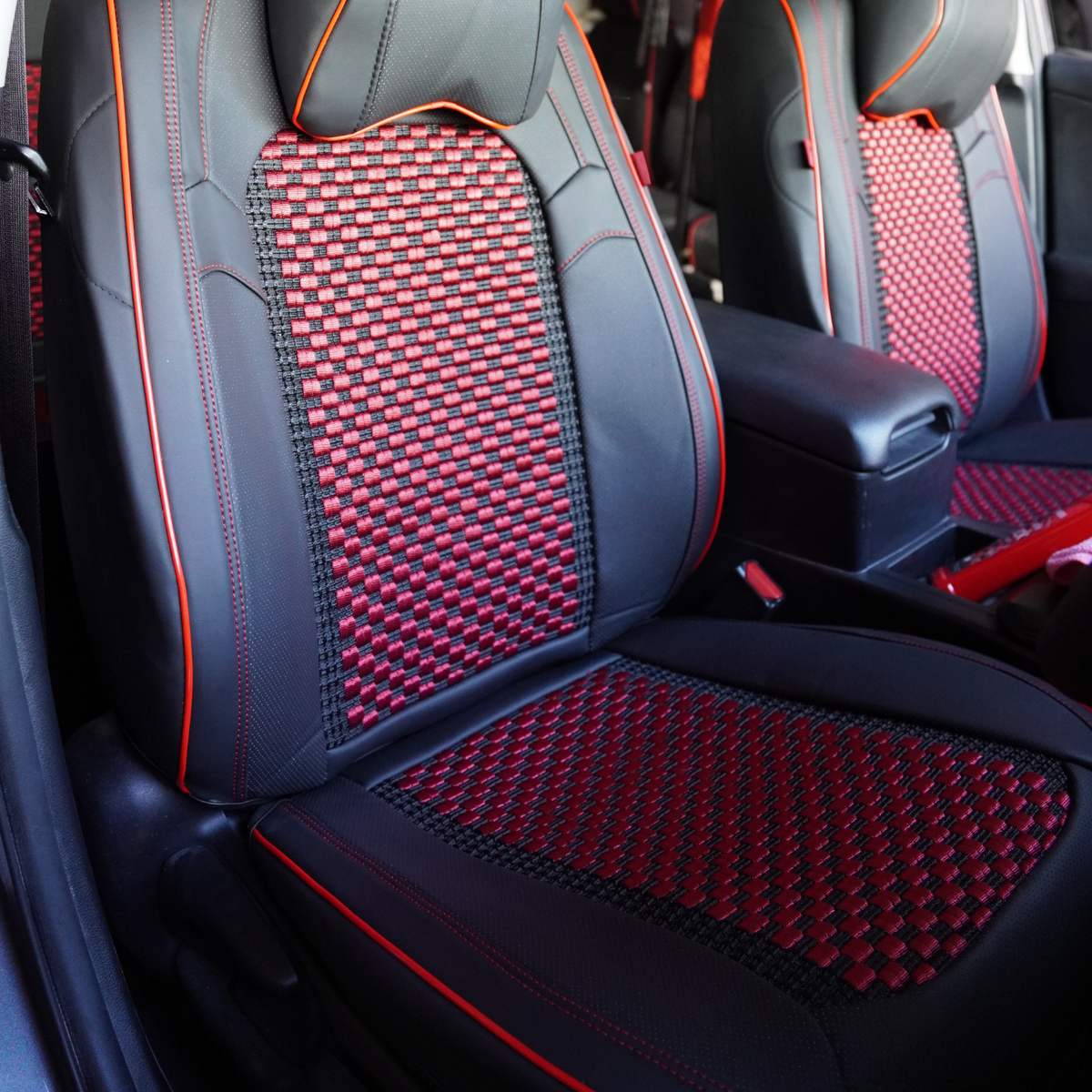 A set of black faux leather car seat covers with red stitching, including a front seat cover, rear seat covers, and a headrest pillow.