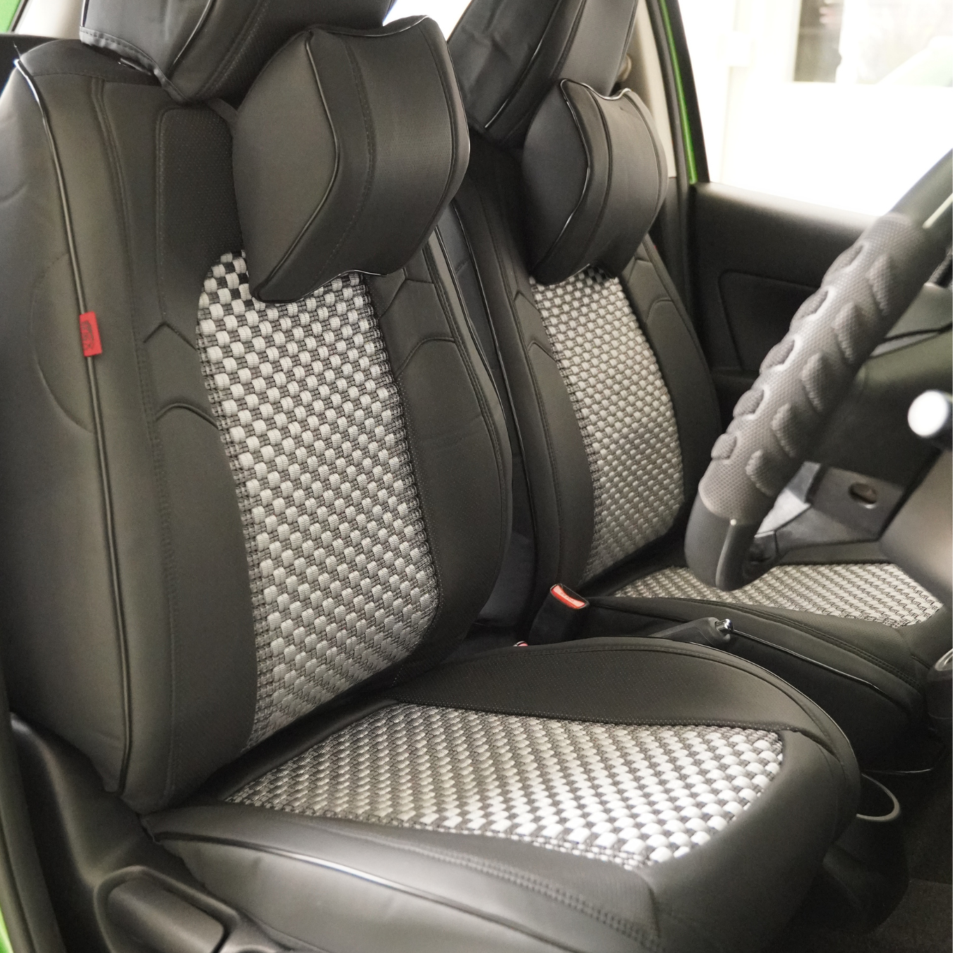 A set of black faux leather car seat covers with red stitching, including a front seat cover, rear seat covers, and a headrest pillow.